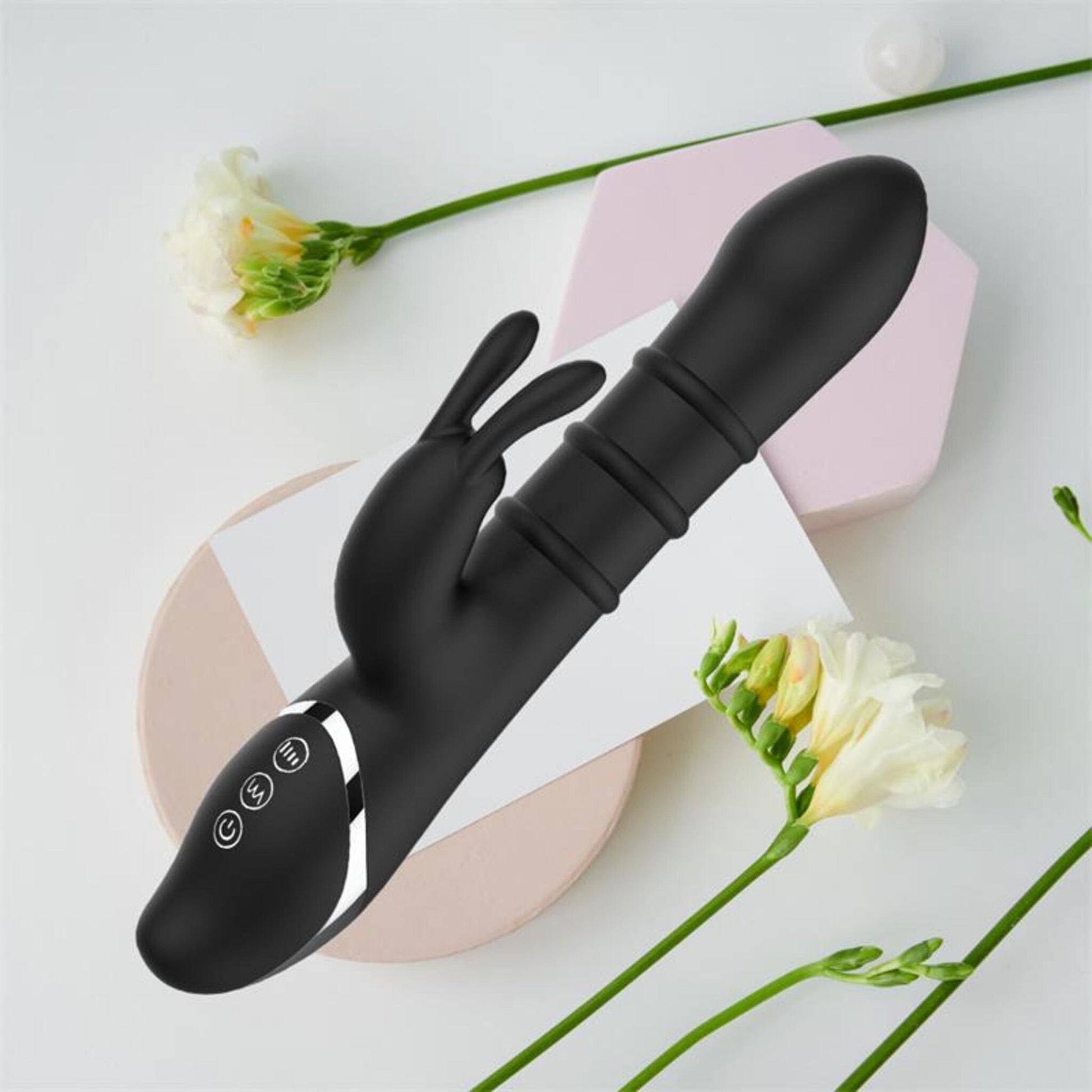 Vibromasseur Lapin Reipo INTOYOU  10 Modes & 3 Anneaux Coulissants vue dans un décor avec des fleurs en arrier plan